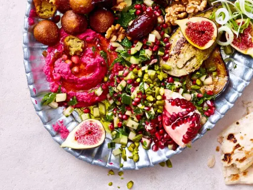 Bunte Mezze-Platte mit Hummus, Falafel, Granatapfel, Feigen und Fladenbrot. Perfekt für ein köstliches Abendessen.