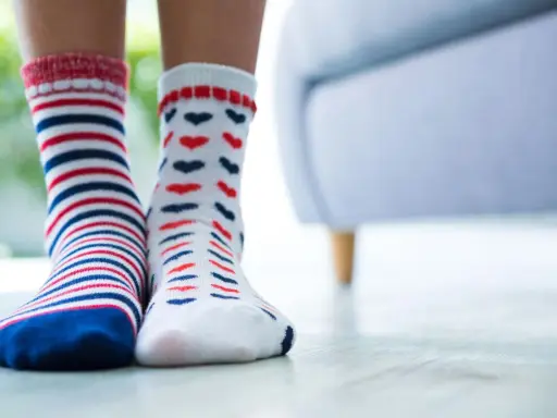 Zwei Paar bunte Socken, gestreift und mit Herzen, warten darauf, mit der richtigen Methode socken sauber bekommen zu werden.