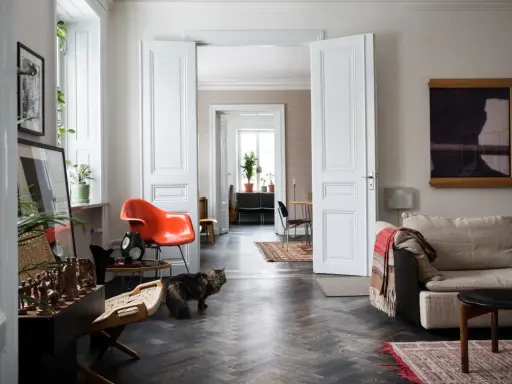 Erika Kangas hem med en katt som smyger förbi en orange stol och en soffa.