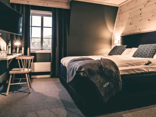 Mysigt rum på vandrarhem i Åre med stor säng, TV och fönster med utsikt.