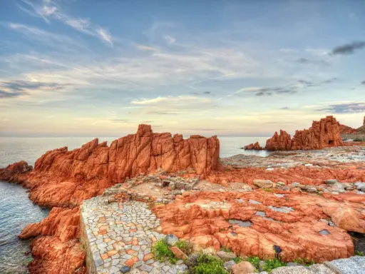 Scogliere rosse e sentiero in pietra a picco sul mare. Un luogo suggestivo da scoprire: Arbatax cosa vedere.