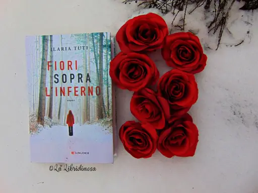 Copertina del libro "Fiori sopra l'inferno" di Ilaria Tuti, con rose rosse su sfondo innevato.