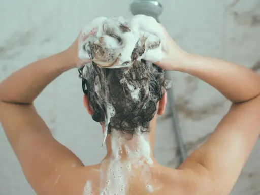Person wäscht sich die Haare mit schaumbildendem Shampoo. Die Stiftung Warentest hat Olaplex-Produkte untersucht.