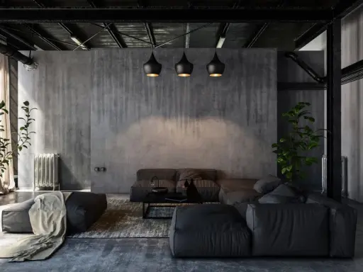 Nowoczesny salon w stylu industrialnym i loftowym. Betonowe ściany, czarne lampy, wygodna, szara sofa i rośliny tworzą surowy, ale przytulny klimat.