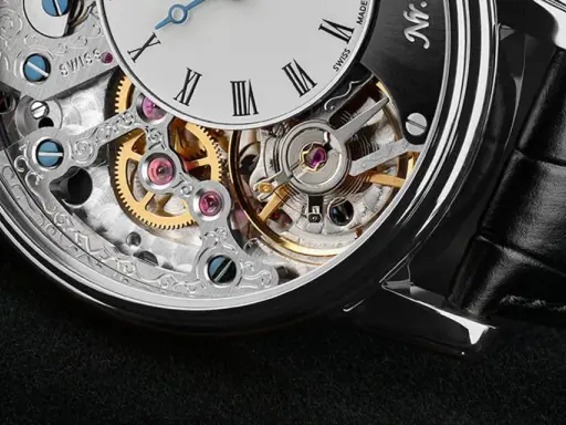 Dettaglio di un orologio scheletrato con ingranaggi dorati e rubini che riducono l'attrito, mostrando a cosa servono i rubini negli orologi.