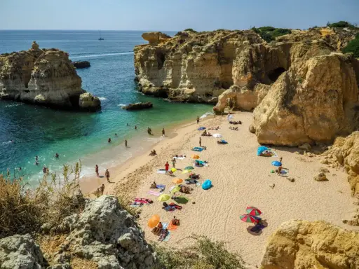 Słoneczna plaża w Algarve, z turkusową wodą i skalnymi klifami. Idealne miejsce, by zobaczyć piękno Portugalii.