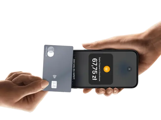 Płatności zbliżeniowe iPhone: karta Mastercard zbliżona do telefonu, wyświetlona kwota 67,75 zł.