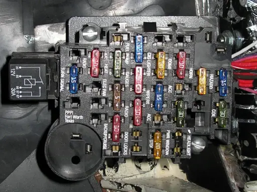 Caja de fusibles de coche con varios fusibles de colores y etiquetas. Aprende cómo quitar un fusible del coche para reparaciones.
