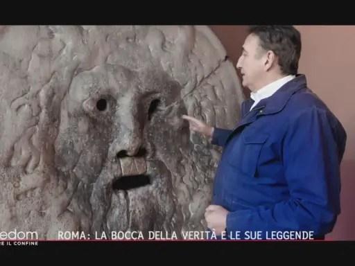 Un uomo indica la Bocca della Verità a Roma, un'antica scultura che si dice morda la mano dei bugiardi. Il suo significato è legato alla giustizia e alla verità.
