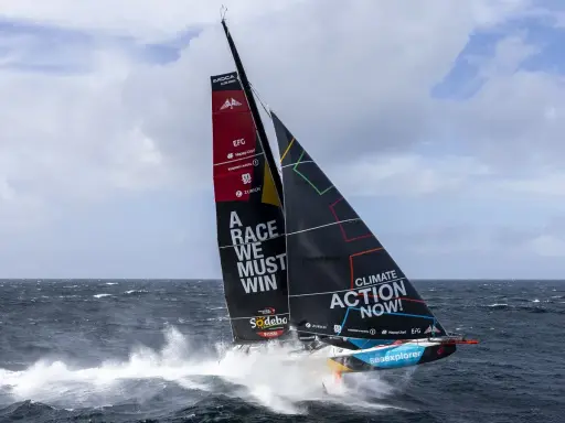 Segelboot mit der Aufschrift "A RACE WE MUST WIN" und "CLIMATE ACTION NOW!" auf dem Weg zum Vendée Globe.