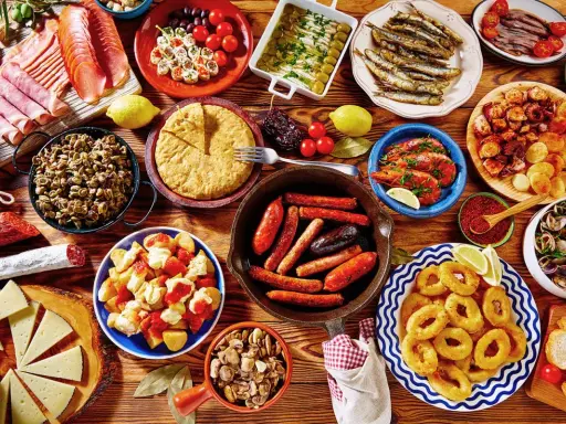 Tapas co to? Kolorowy stół pełen hiszpańskich przekąsek: kiełbaski, krewetki, owoce morza, tortilla, sery i wędliny. Prawdziwa uczta!