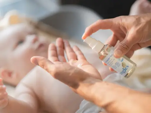 En hand sprutar olja i en annan hand, redo att smörja en bebis. Kanske för att lindra skorv bebis.