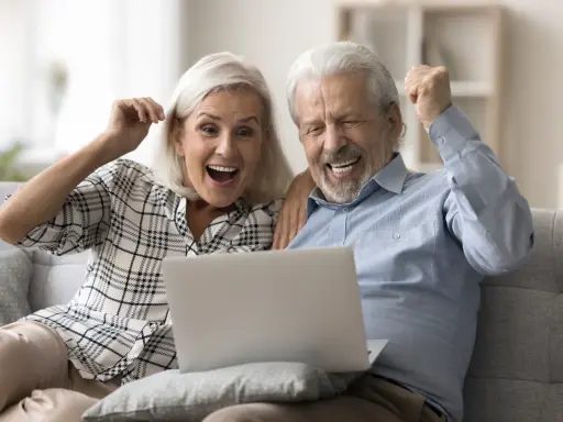 Szczęśliwi seniorzy sprawdzają na laptopie przeliczenie emerytury rocznik 1949 do 1953.