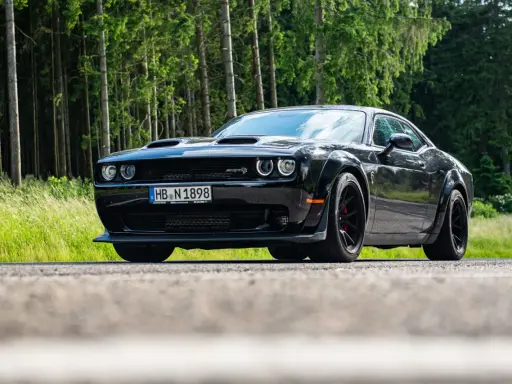 Schwarzer Dodge Challenger SRT Hellcat Redeye parkt am Waldrand.