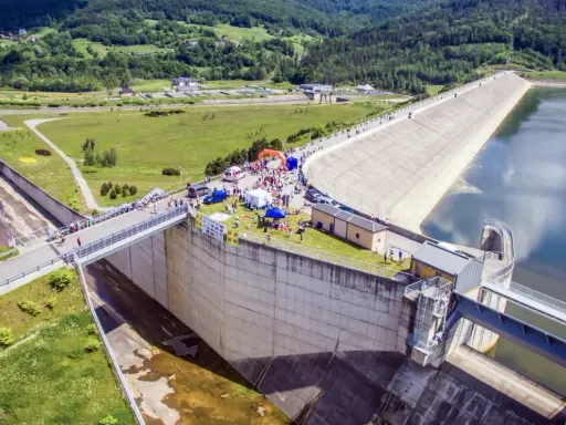 Impreza nad Jeziorem Mucharskim. Ludzie spacerują po zaporze, podziwiając widoki i korzystając z atrakcji.