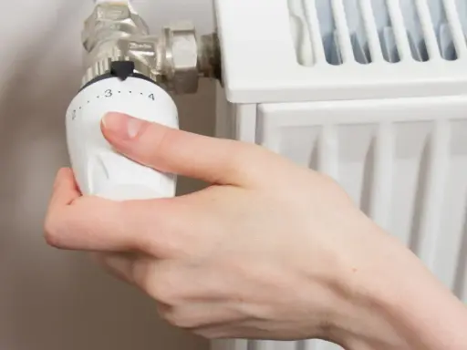 Mano ajustando el termostato para abrir radiador derecha o izquierda.