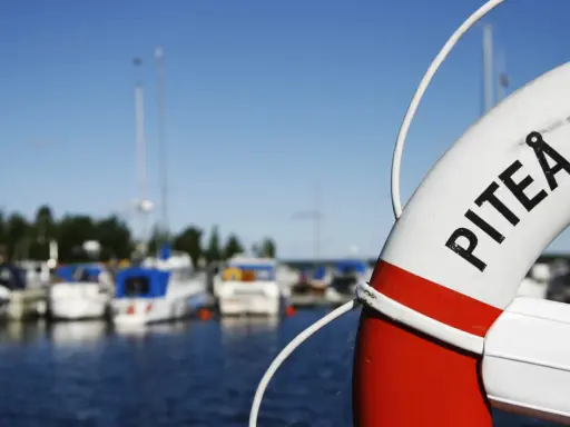 Livboj med texten PITEÅ K visar en hamn med båtar. Ett perfekt ställe att besöka Piteå på!