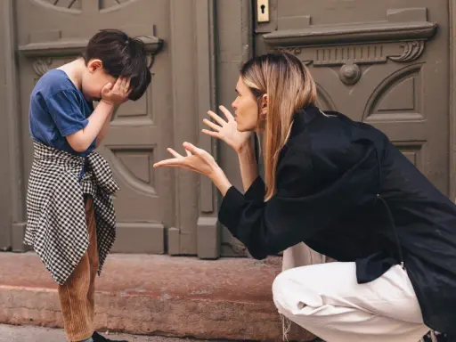 Madre explica a su hijo cómo poner límites a los niños. El niño se tapa la cara con las manos, visiblemente afectado.