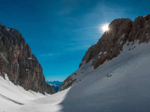 Sole che filtra tra le vette innevate, un invito a scoprire cosa vedere in Friuli Venezia Giulia, tra sentieri e panorami mozzafiato.