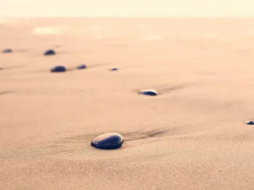 Spacer dzika plaża. Kamienie na piasku, szum fal. Kto śpiewa? Może wiatr?
