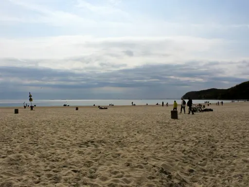 Plaża z ludźmi spacerującymi i odpoczywającymi. Idealny pomysł na weekend nad morzem.