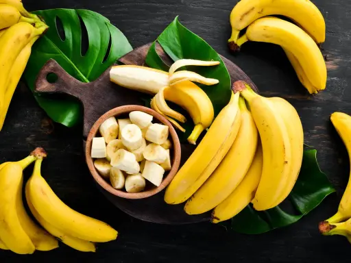 Pęki dojrzałych bananów, jeden obrany i pokrojony w miseczce. Zastanawiasz się, ile węglowodanów ma banan?