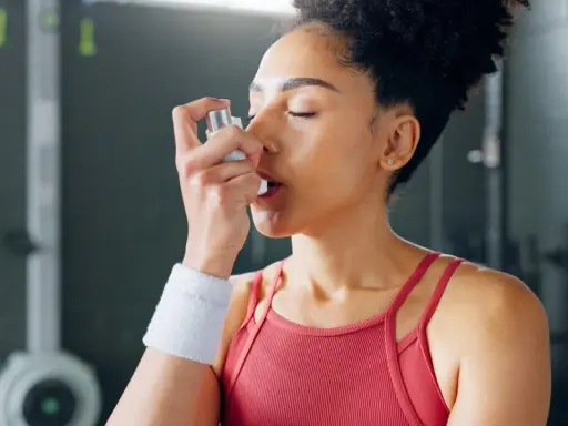 Frau mit Inhalator im Fitnessstudio. Sport bei COPD kann mit richtiger Vorbereitung möglich sein.