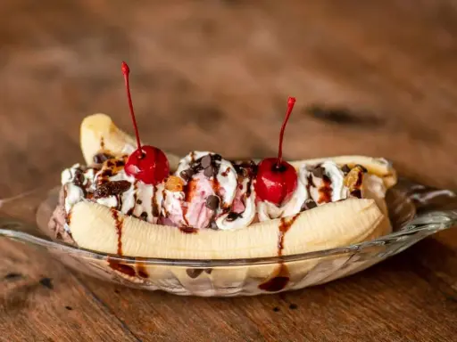 Un déliceux banana split avec glace, crème fouettée, pépites de chocolat et cerises. Une recette parfaite pour un dessert gourmand.