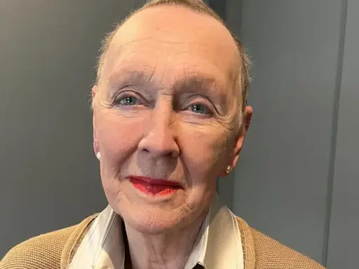 Åldfrun Ebba von Mecklenburg, med sina blå ögon och röda läppar, bär en beige kofta och ett pärlhalsband.
