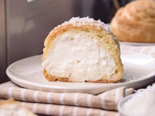 Bignè ripieno di crema soffice, cosparso di zucchero a velo che ricorda un fiocco di neve.