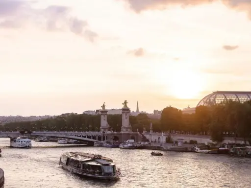 Boote auf der Seine bei Sonnenuntergang, eine malerische Szene, die die beste Reisezeit für Paris widerspiegelt.