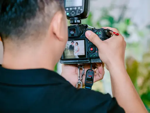 Fotograf robi zdjęcie parze młodej na ekranie aparatu.