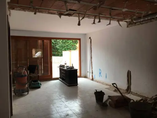 Interior de una casa de pueblo en plena reforma. Se ven materiales de construcción, herramientas y un aspirador.