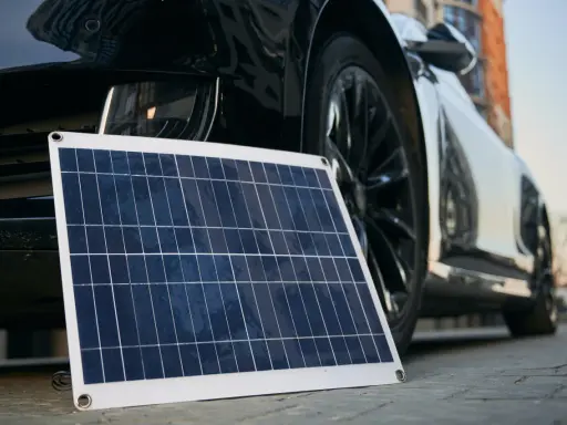 Panel solar portátil junto a un coche eléctrico, listo para cargar en casa.
