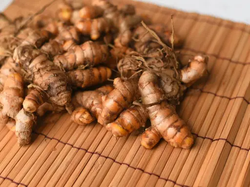 Kłącza kurkumy, znanej jako turmeric co to, leżą na bambusowej macie.