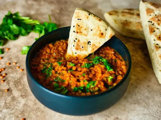 Herzhafte Linsenrezepte: Ein dampfender Linseneintopf mit frischer Petersilie und Fladenbrot.