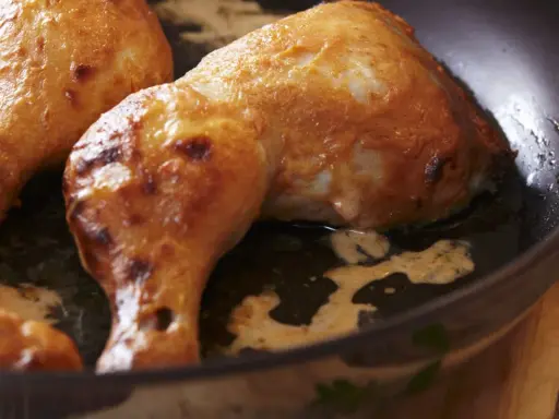 Cosce di pollo dorate e succulente cuociono in padella, emanando un profumo invitante.