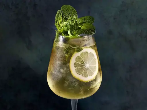 Un verre de Hugo Spritz rafraîchissant, garni de menthe fraîche et d'une tranche de citron. Parfait pour une recette d'été.