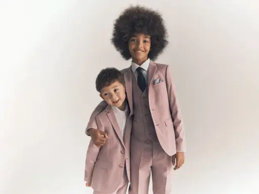 Two boys in matching dusty rose suits, showing what ring bearers wear: tailored jackets, vests, shirts, and ties.