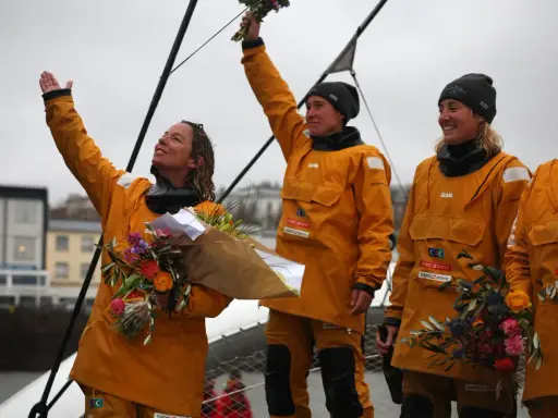 Des femmes en cirés jaunes célèbrent la fin du célèbre projet, bouquets à la main.