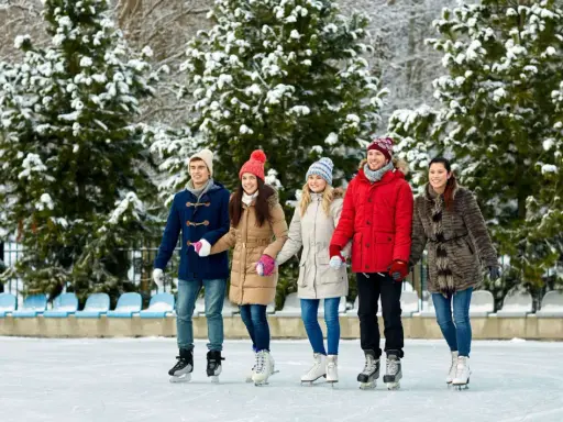 Pięcioro przyjaciół na lodowisku, ubranych ciepło, pokazuje, jak się ubrać na lodowisko kryte.