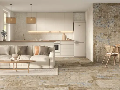 Elegante salón-cocina con sofá beige, mesa de centro de madera y suelos de cemento con un diseño rústico y texturizado.