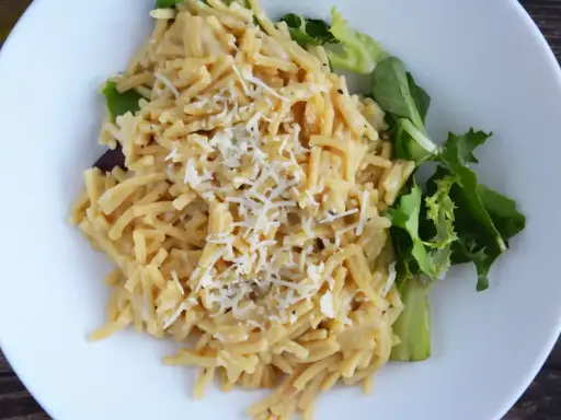 Pyszne cacio e pepe z tartym serem i świeżą sałatką na białym talerzu.