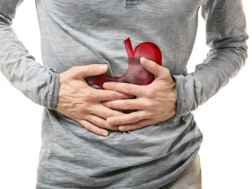 Uomo con mani sullo stomaco, dove un'immagine rossa evidenzia un possibile tumore allo stomaco.