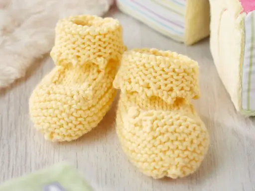 Patucos dos agujas de lana amarilla, perfectos para abrigar los pies de un bebé.