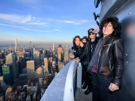 Les membres du groupe KISS posent sur un gratte-ciel new-yorkais, offrant une vue imprenable sur la ville.