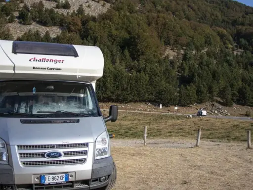 Camper parcheggiato in un'area panoramica della Calabria, con boschi e montagne sullo sfondo. Un'avventura in camper indimenticabile.