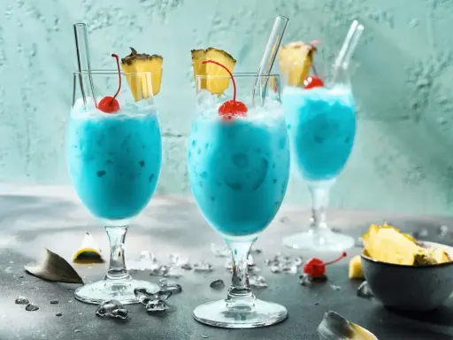 Erfrischende blaue Swimmingpool-Cocktails mit Ananas und Kirschen, bereit für den Sommer.