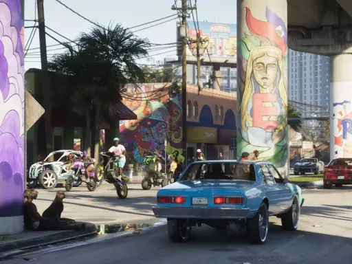 Kolorowe murale zdobią filary wiaduktu w słoneczny dzień. Na ulicy ruchliwie: ludzie na motocyklach i quadach, samochody, psy. To scena z GTA 6 online.