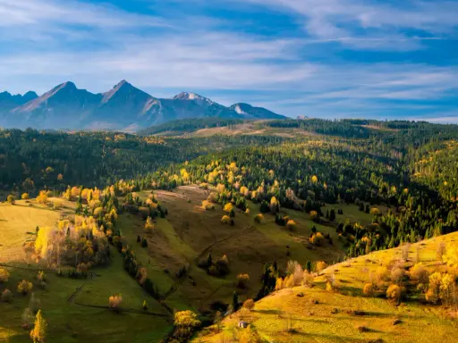 Jesienne Tatry Słowackie zachwycają kolorami. Widok na łagodne wzgórza i lasy, idealne na szlaki dla średnio zaawansowanych.
